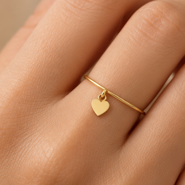 Bague breloque cœur en or jaune 18K portée sur main claire