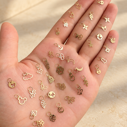 Pendentifs dorés miniatures présentés sur la main