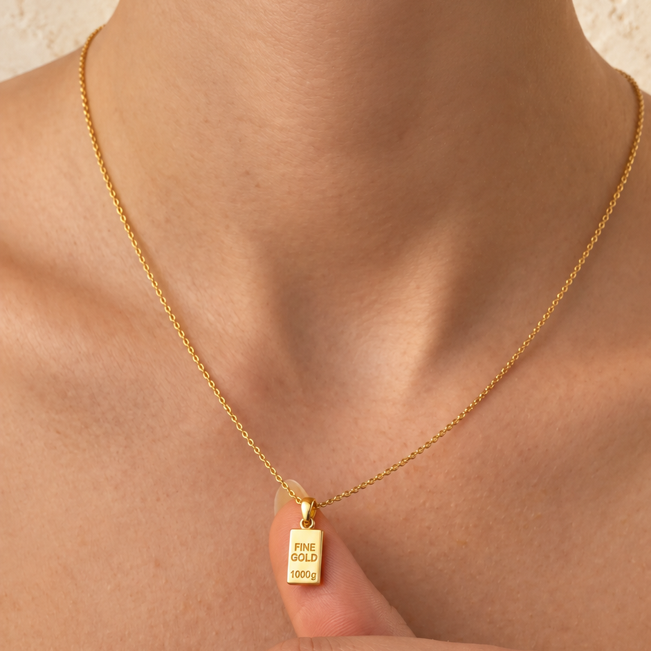 Pendentifs lingots miniatures — Ensemble de petits lingots en Or avec bélières, présentés dans la main.