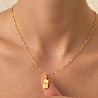 Pendentifs lingots miniatures — Ensemble de petits lingots en Or avec bélières, présentés dans la main.