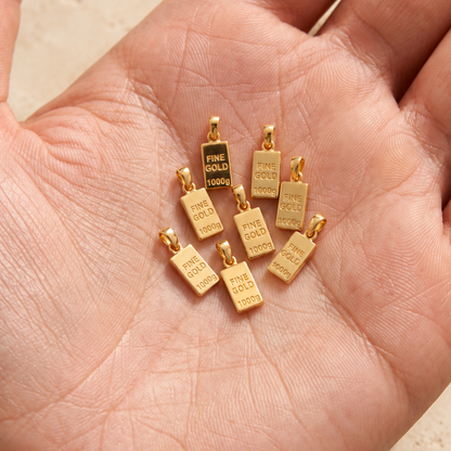 Pendentifs lingots miniatures — Ensemble de petits lingots dorés avec bélières, présentés dans la main.
