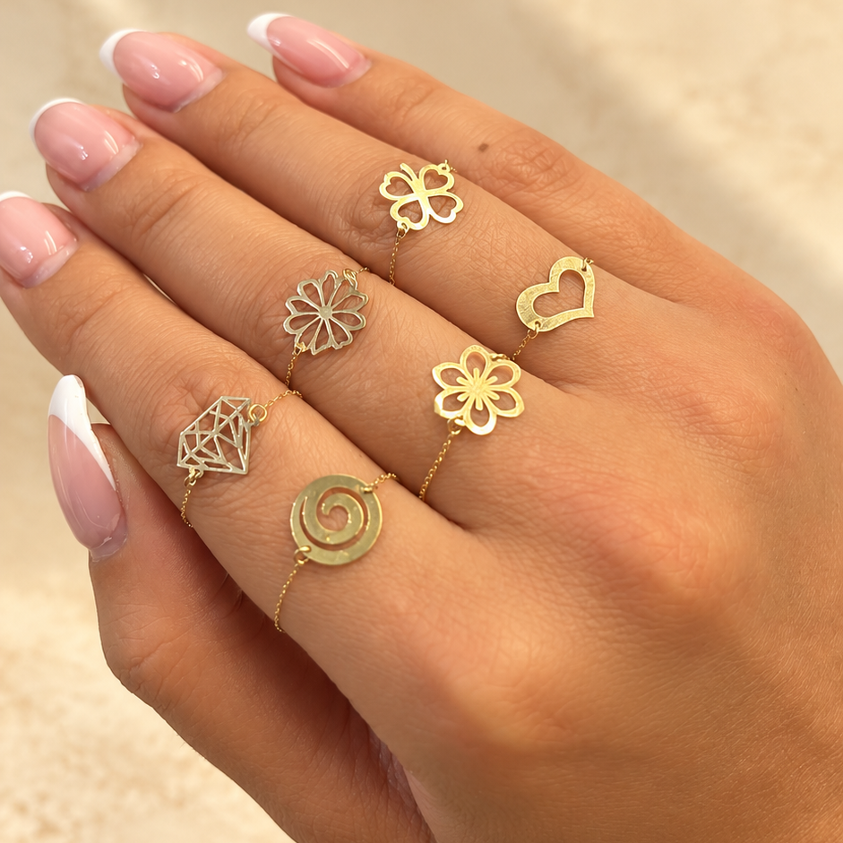 Assortiment de six bagues fines dorées à fleurs, cœur, trèfle et spirale