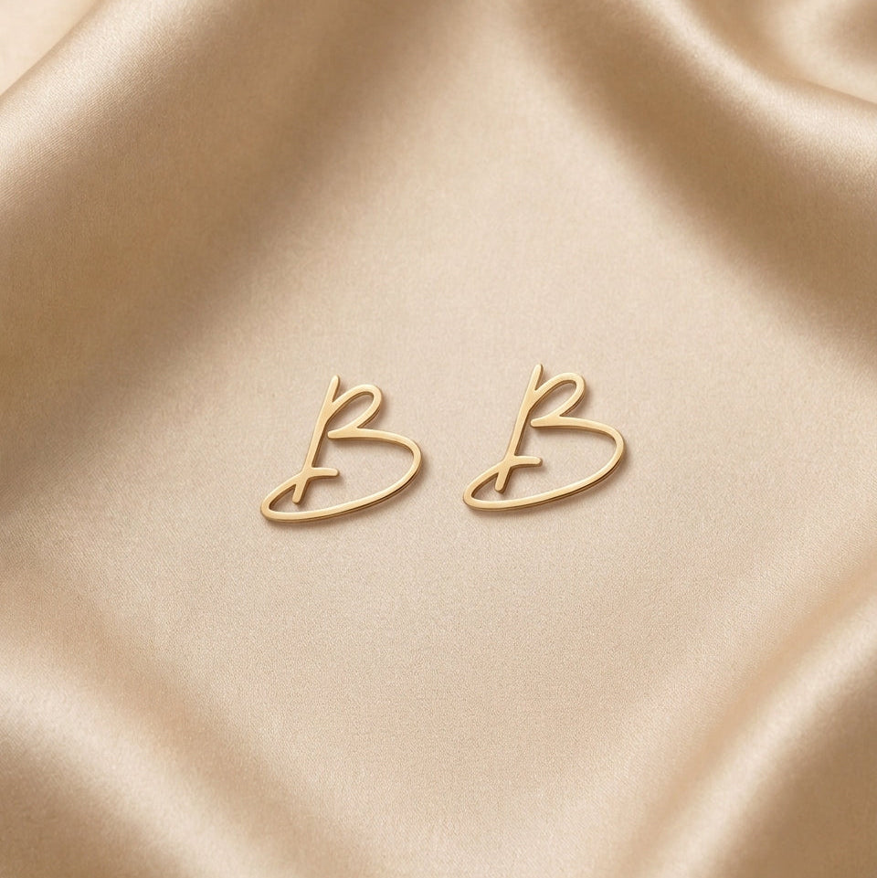 Éléa – Boucles d'oreilles initiale latine en or - Or massif 18 carats - Or jaune - photographié sur un fond en satin