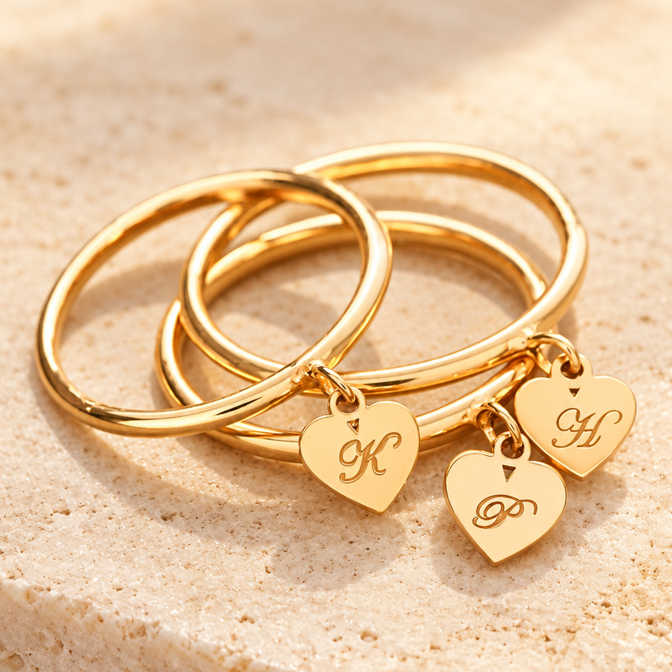 Trois bagues dorées à pendentifs cœur avec initiales gravées
