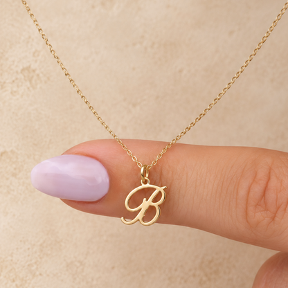 Collier initiale B cursive — Chaîne fine et pendentif lettre B dorée.