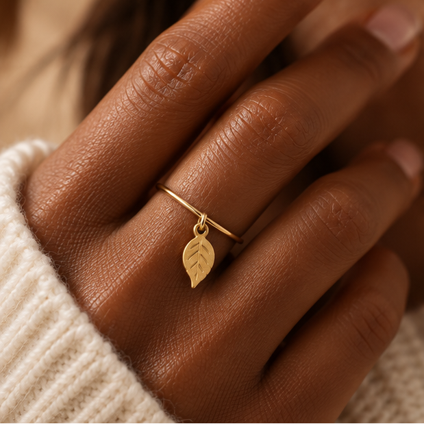 Bague breloque feuille en or jaune 18K portée sur main foncée