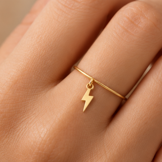 Bague breloque éclair en or jaune 18K portée sur main claire