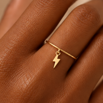 Bague breloque éclair en or jaune 18K portée sur main foncée
